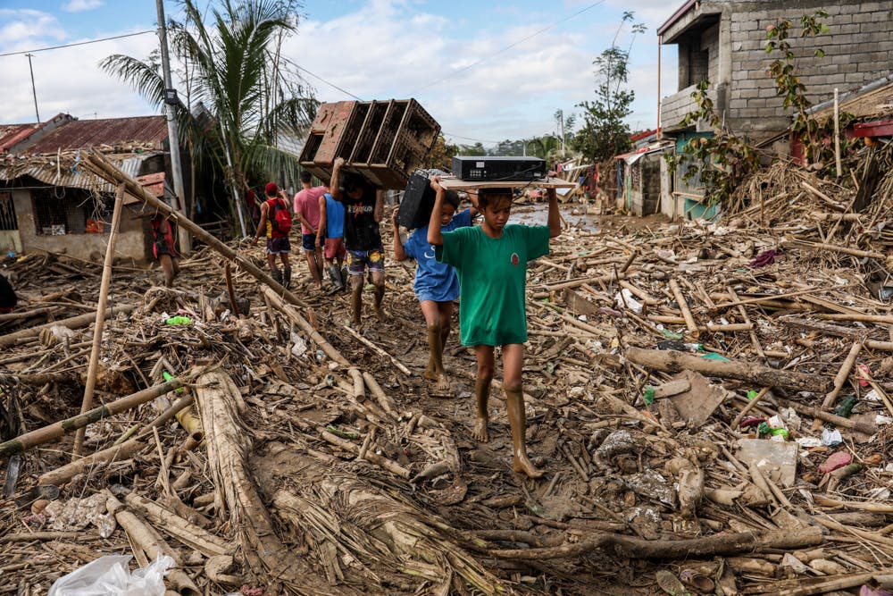 Residents of Kasiglahan Village in Rodriguez, Rizal, walk through the wreckage caused by Typhoon Ulysses. Image: Greenpeace Philippines