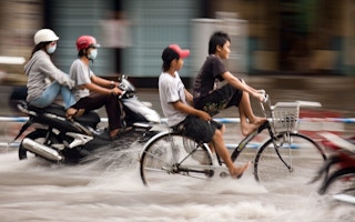 Bikers ride through flood in Vietnam.