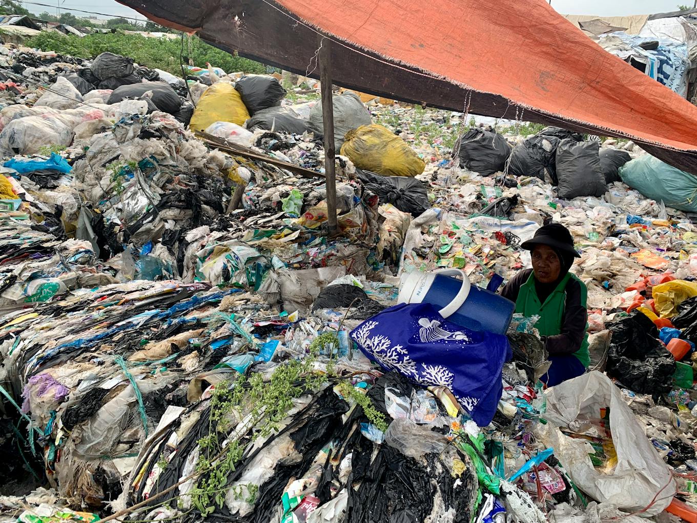 An elderly woman distributes plastic waste at the Bantar Gebang landfill