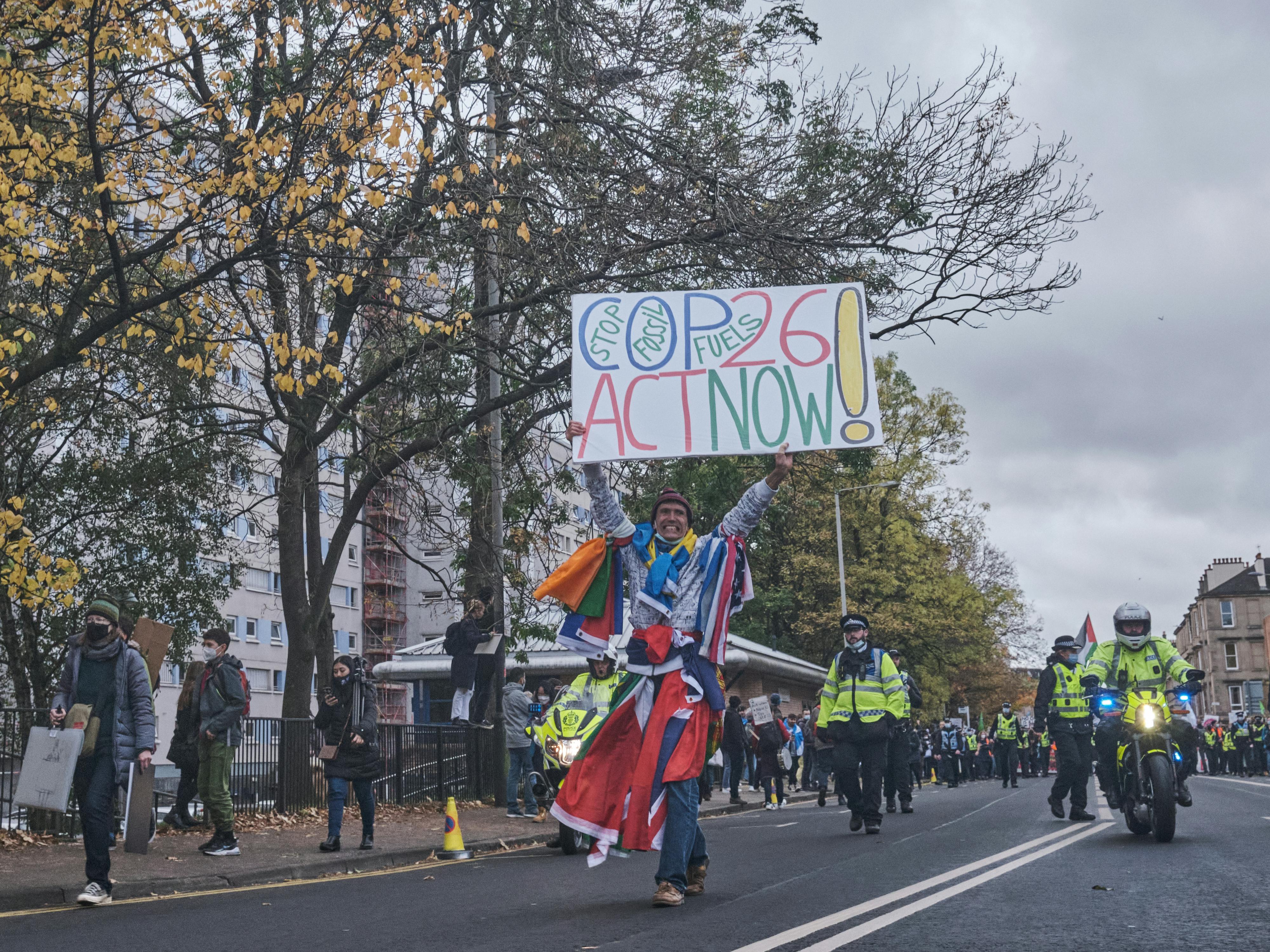 A man carries a sign asking world leaders to stop fossil fuels, COP26