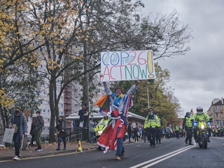 A man carries a sign asking world leaders to stop fossil fuels, COP26