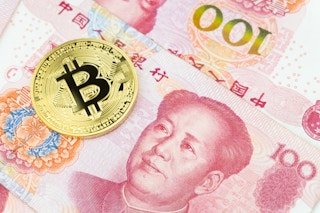 Golden bitcoin with Chinese yuan banknotes