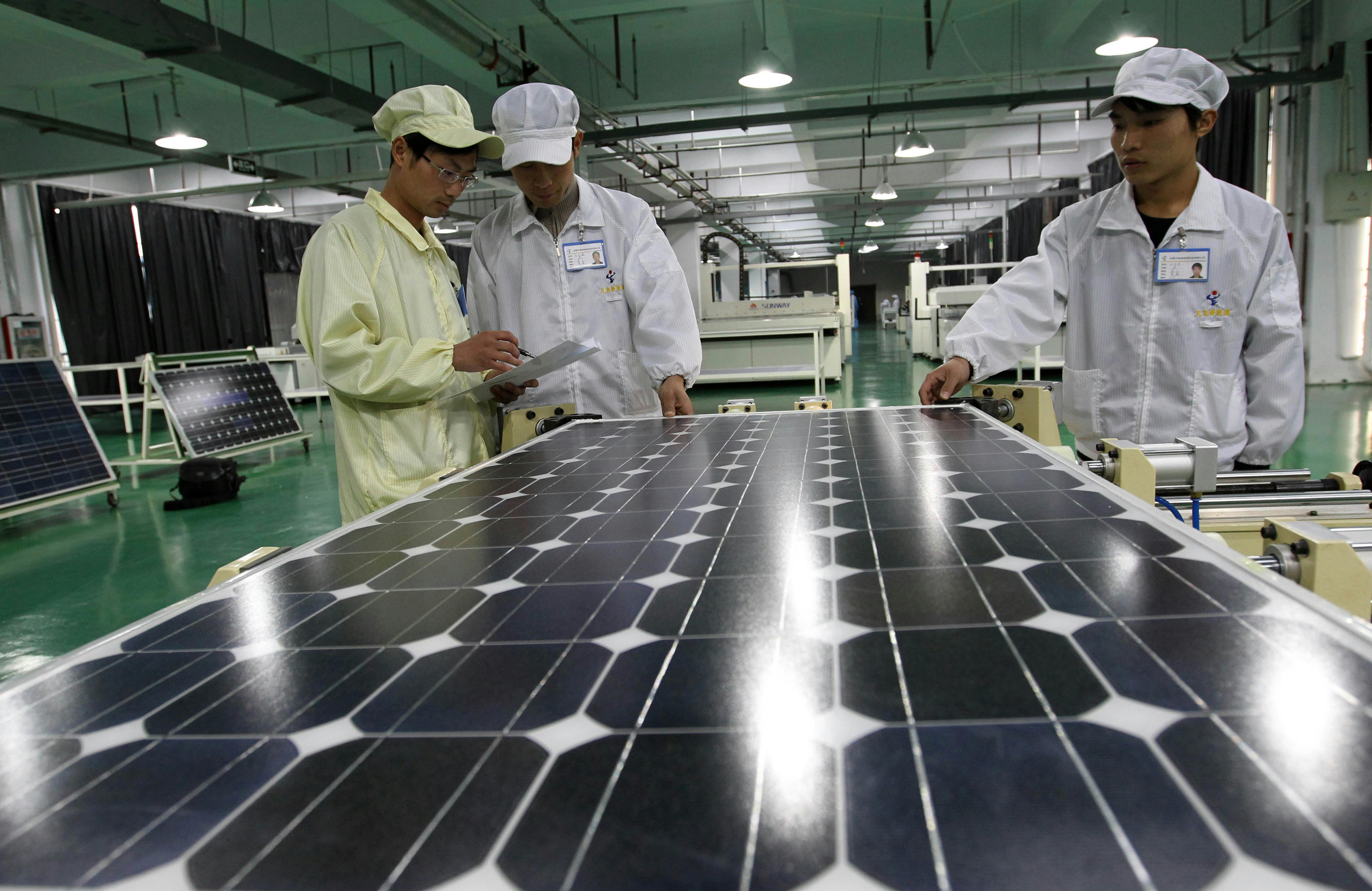 Chinese factory workers manufacture solar panels