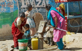 women and children pump water to plastic containers in Orchha, India