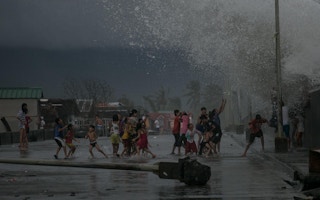 Children gather by the seawall as strong waves brought by Typhoon Kammuri