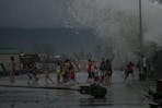 Children gather by the seawall as strong waves brought by Typhoon Kammuri