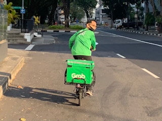 A GrabFood driver riding an e-scooter in Little India, Singapore.