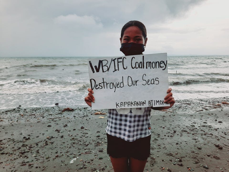 A resident of Atimonan, Quezon raises a placard protesting how the IFC-funded Atimonan One Energy power station has polluted Lamon Bay