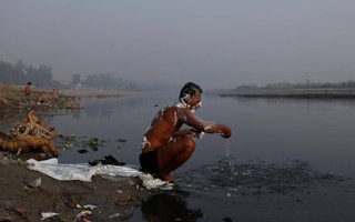man washes in polluted water