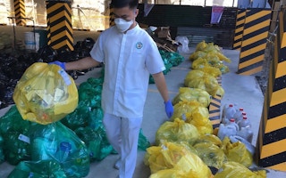 cleaner collects medical waste at the St. Paul's Hospital in Iloilo, Philippines.