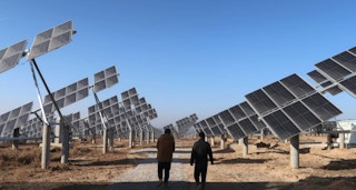Workers walk at a solar power station in Tongchuan, Shaanxi province, China