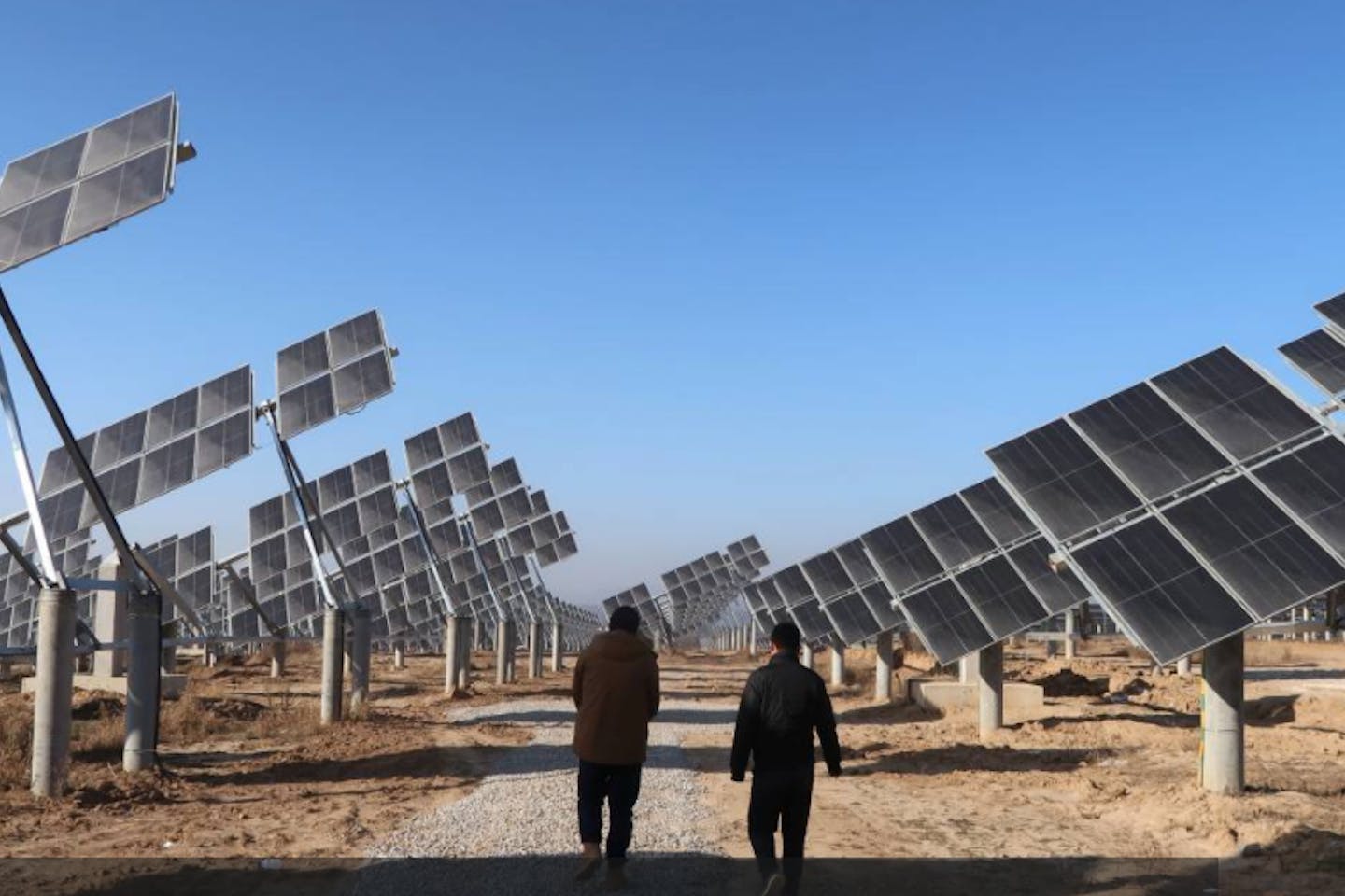 Workers walk at a solar power station in Tongchuan, Shaanxi province, China