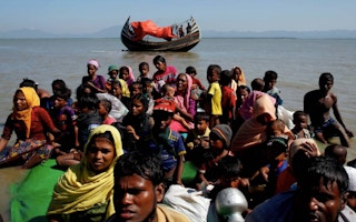 Rohingya refugees sit on a makeshift boat as they are interrogated by the Border Guard Bangladesh