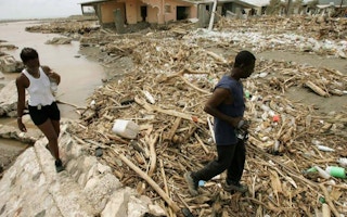 Jamaicans walk near houses September 13, 2004, which were destroyed by Hurricane Ivan
