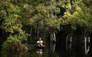 A fisherman rows his boat on a peatland river in the Kerumutan protected forest , Indonesia