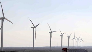 A truck moves past power-generating wind turbines