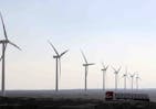 A truck moves past power-generating wind turbines