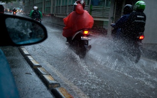 Motorbikes flow through flood water in Jakarta