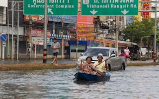 A couple paddle through a flooded road in Bangkok, Thailand.