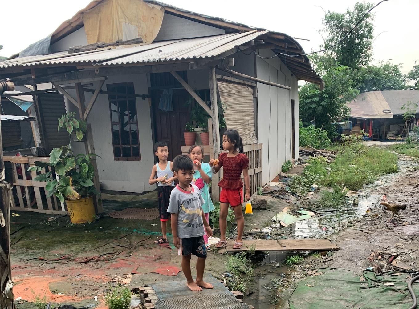 Children chat outside their home in landfill village in West Java, Indonesia.