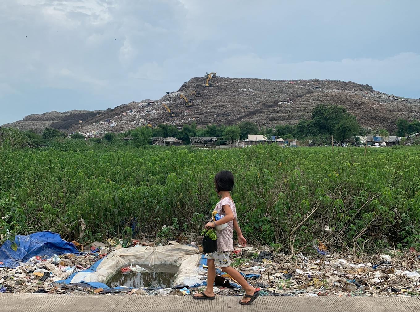 A young girl walks passed Bantar Gebang landfill