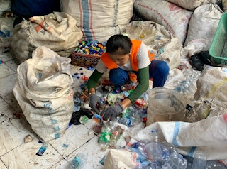 A woman sorts through plastic bottles in a recycling facility run by Prevented Ocean Plastic in Bali, Indonesia.