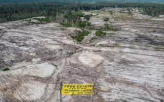 A protest banner reading “Food Estate Feeding Climate Crisis” lies on land cleared for food estate project in Kalimantan in 2022.