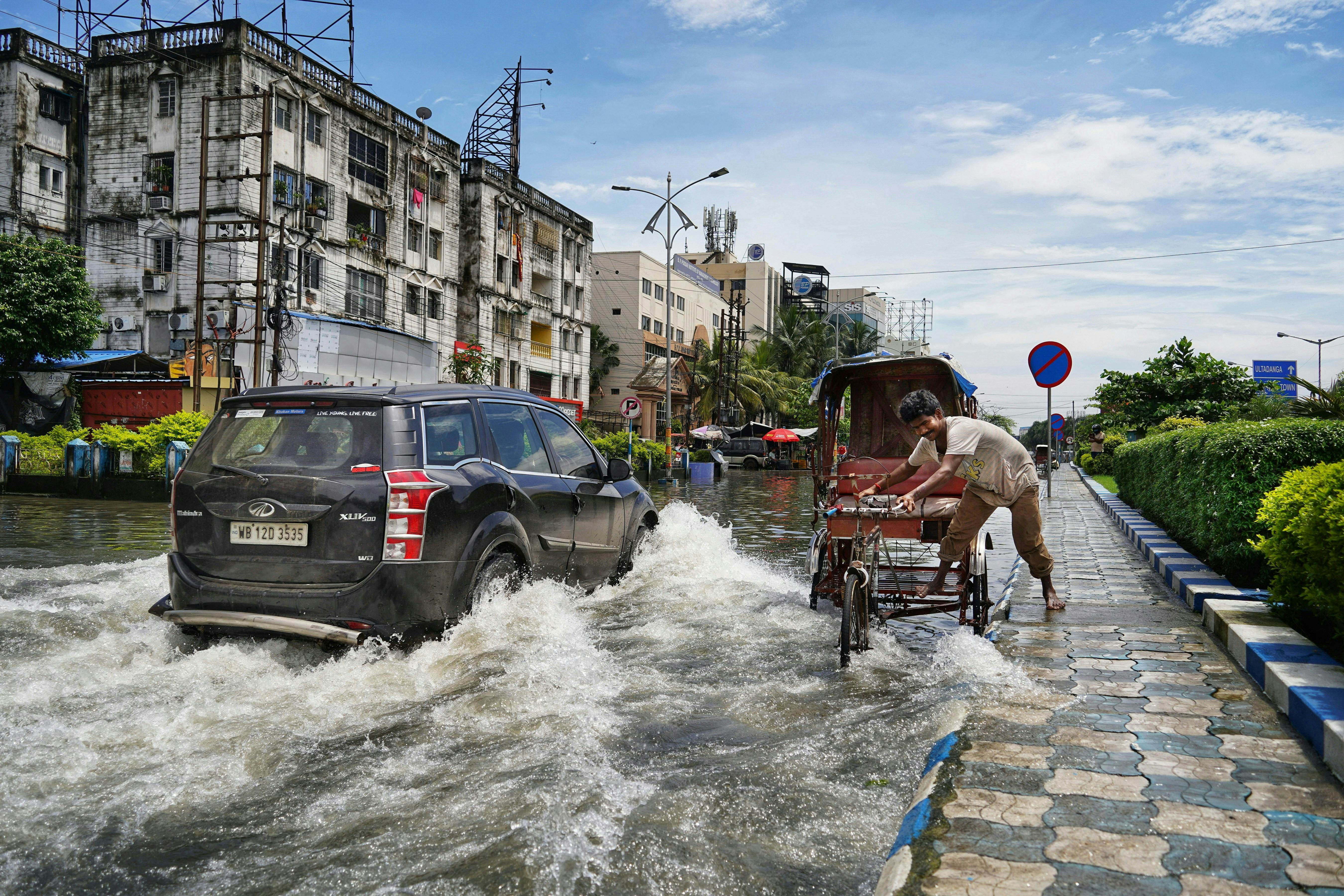 A man pushing a wagon through a flooded-street in Kolkata