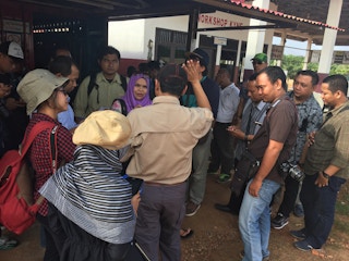 Journalists at a palm oil plantation question a corporate communications official.