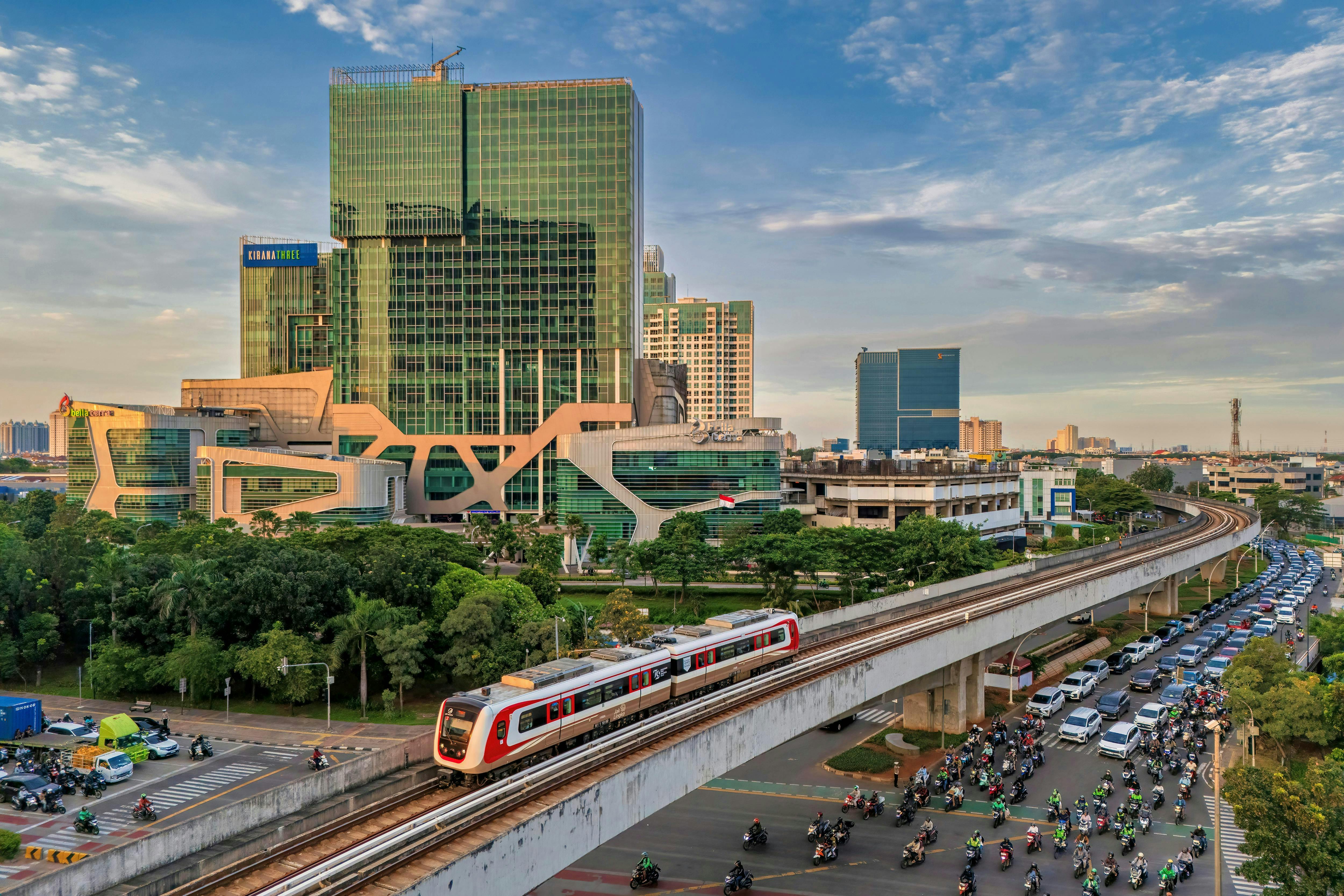 Elevated train passing through a bustling Jakarta cityscape with modern buildings