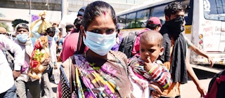 A woman with her baby at a bus stop in Delhi. Women in developing countries are being hit hardest by the coronavirus pandemic. Image: rajput/​SOPA Images/​Shutterstock