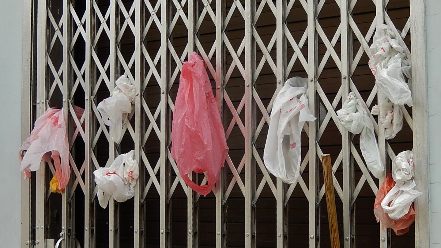 Single-use plastic bags are stuffed into a grate door in Little India, Singapore. Only 6 per cent of the city-state's plastic waste was recycled last year. Image: Michael Coghlan/Flickr