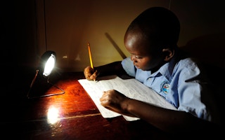 boy studying under solar lamp