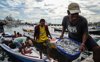 Fishermen unloading buckets of fish from their boats in Makassar, South Sulawesi, Indonesia