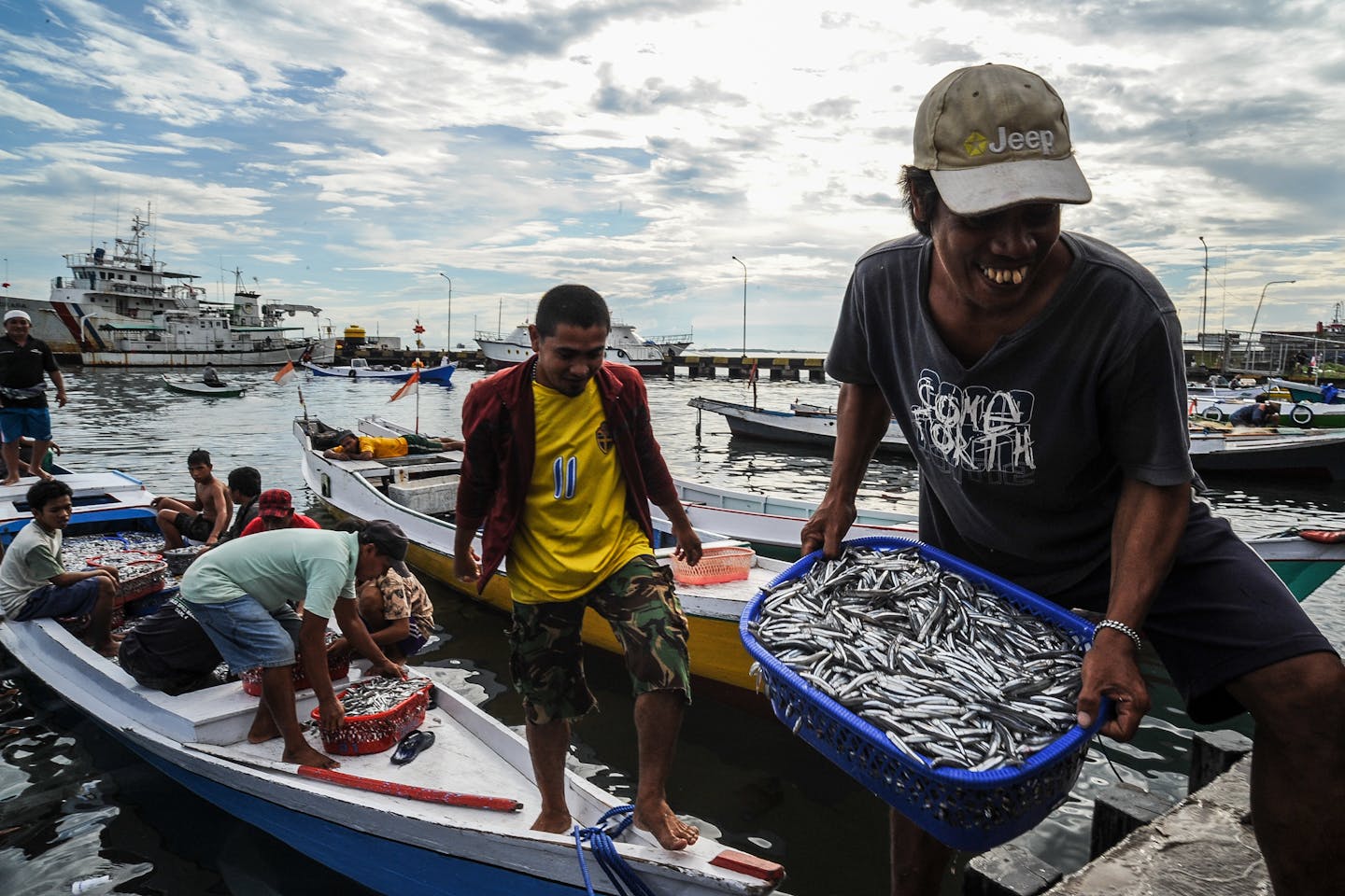 Fishermen unloading buckets of fish from their boats in Makassar, South Sulawesi, Indonesia