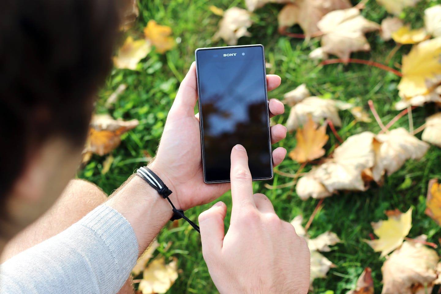 Guy using smartphone against green backdrop of some sort
