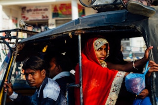 A woman rides in the back of an auto-rickshaw in Uttar Pradesh, India.