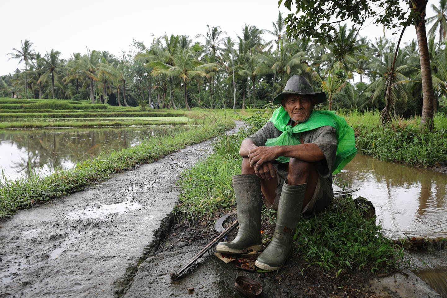 A farmer in Ubud, Bali, Indonesia sits beside his crops