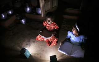 Girls in a village in India read books after dark with the help of solar lamps