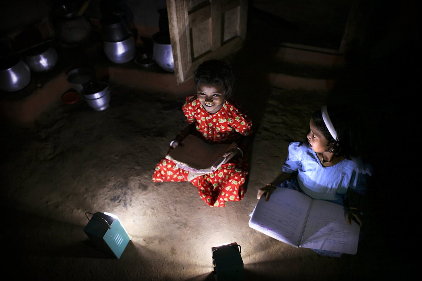 Girls in a village in India read books after dark with the help of solar lamps