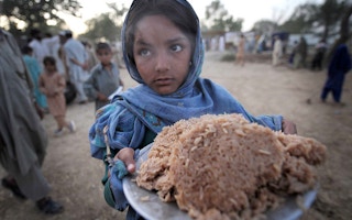 child holds a plateful of rice