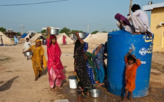 Women and children displaced by floods in Pakistan queue for water. 
