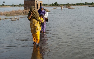 family crosses flooded street in Pakistan