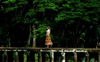 woman walks past trees