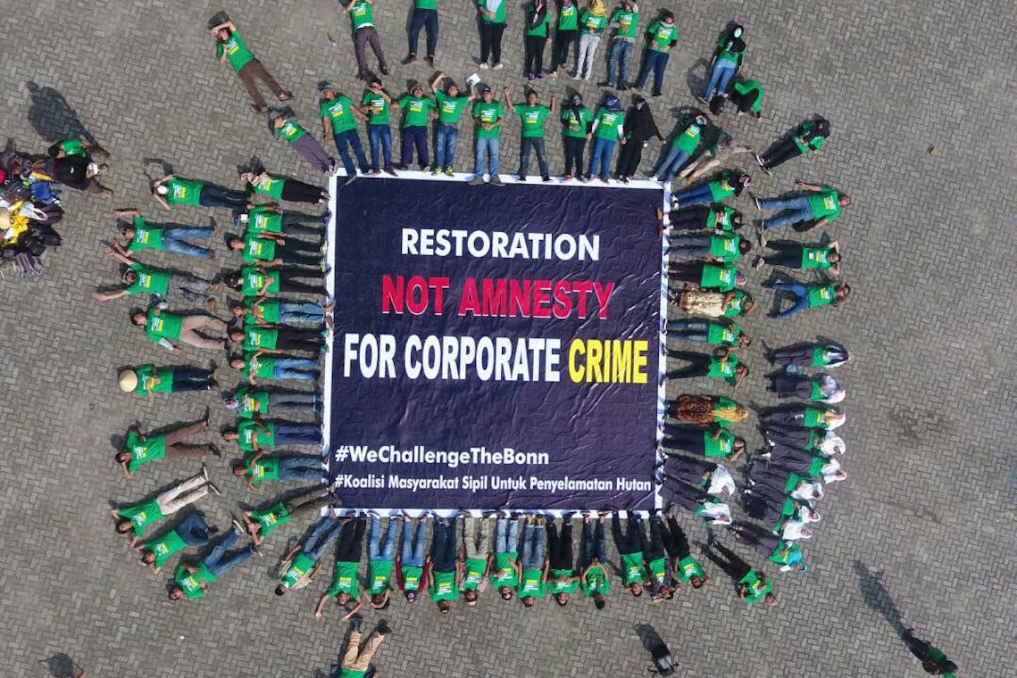 Protester lie outside the Asian launch of the Bonn Challenge, calling on the organisation not to be used to mask the "corporate crime' of pulp and paper companies that are threatening the environmental and livelihoods in South Sumatra: Image: Hutan Kita Institute