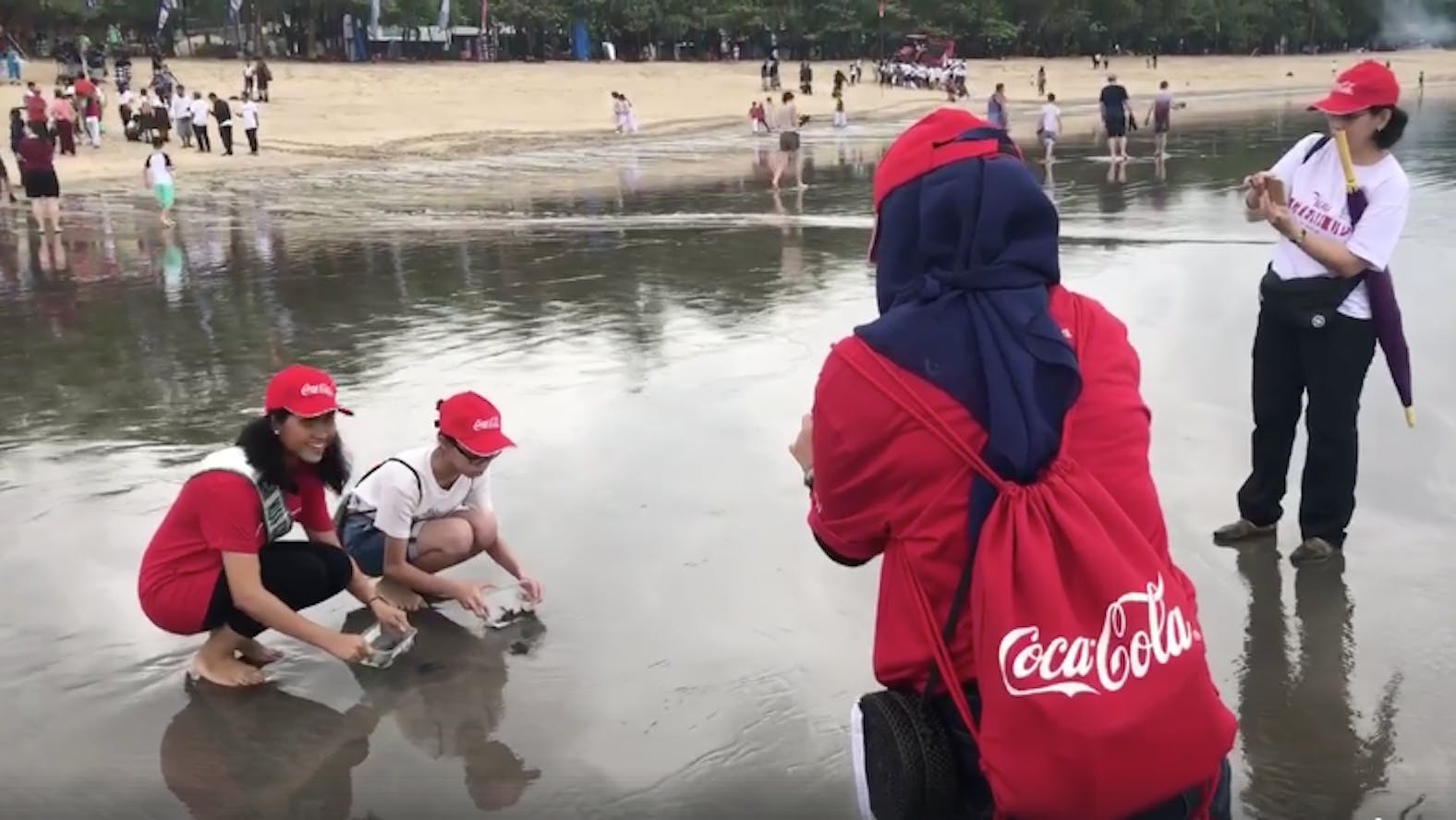 Wearing Coca-Cola branded t-shirts, Miss Indonesia poses for the cameras while releasing a turtle on Kuta Beach, Bali