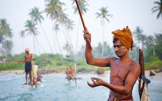 A Sri Lankan traditional stilt fisherman gets ready for the day's catch.