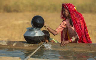 A woman fills her container with water in India.
