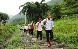 school children walk on rice paddies in India